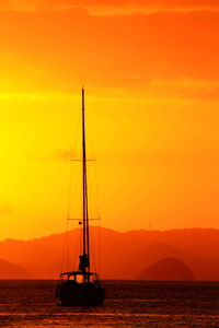 Sailboat sailing on sea against orange sky during sunset