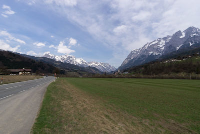 Empty road leading towards mountains against sky