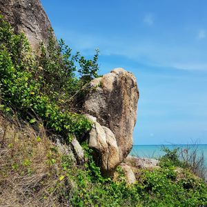 Rock formation by sea against sky