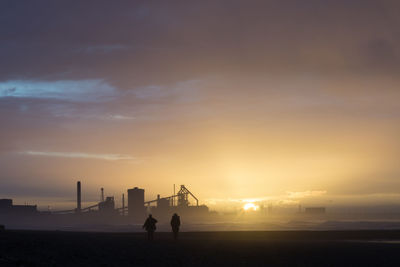 Silhouette people standing on land against sky during sunset