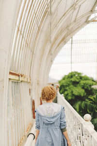 Rear view of woman standing against white wall