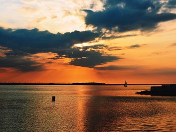 Scenic view of sea against cloudy sky at sunset