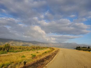 Scenic view of dirt road against sky