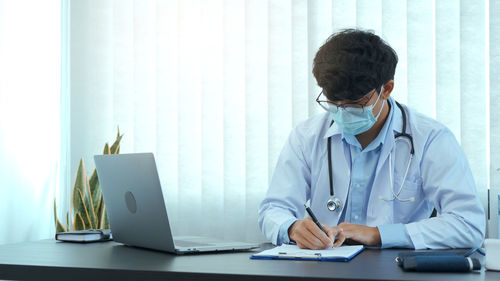 Midsection of man using smart phone on table