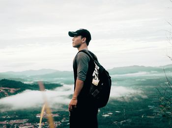 Side view of man standing on mountain against sky