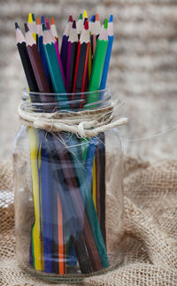 Colored pencils in glass jar on rustic table