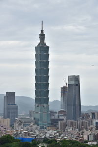 Buildings in city against cloudy sky