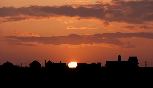 Silhouette city against sky during sunset