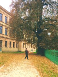 Rear view of a man walking on road along buildings