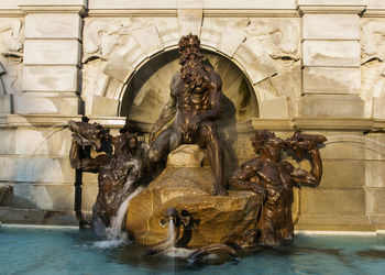 Statue by fountain against building