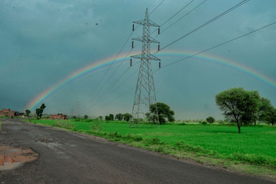 Scenic view of field against rainbow in sky