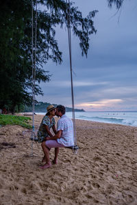 Rear view of couple sitting on beach