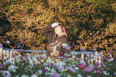 Low angle view of young woman amidst flowering plants