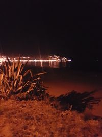 Illuminated lights on beach against sky at night