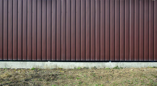 Closed metal fence on field against wall