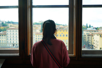 Rear view of woman looking through window