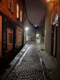 Empty alley amidst buildings in city at night