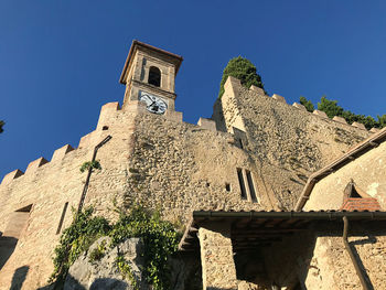 Low angle view of old building against clear blue sky