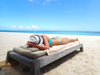 Woman lying on lounge chair at beach