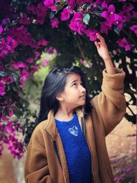 Side view of young woman looking away against plants