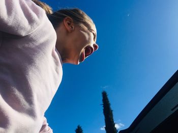 Low angle view of screaming girl against sky in summer