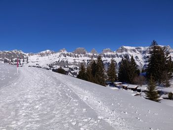 Scenic view of snow covered mountains against clear blue sky