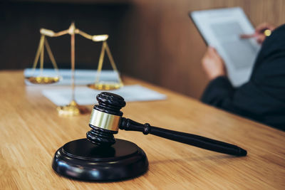 Midsection of lawyer with data sitting by gavel and weight scale on desk