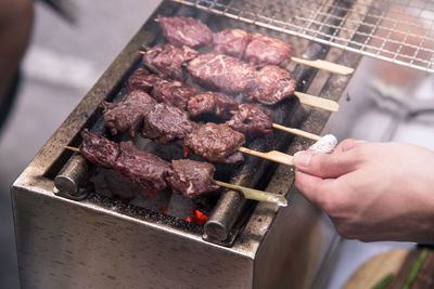 Close-up of person preparing food on barbecue grill