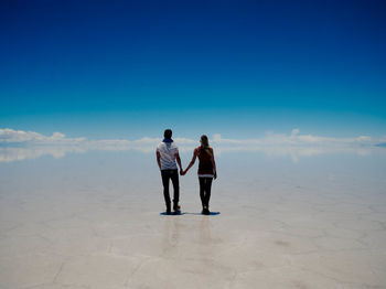 Rear view of couple walking on beach