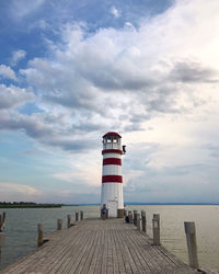 Lighthouse on pier by sea against sky
