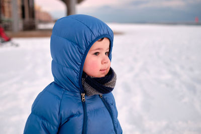 Cute baby boy in snow on an empty beach