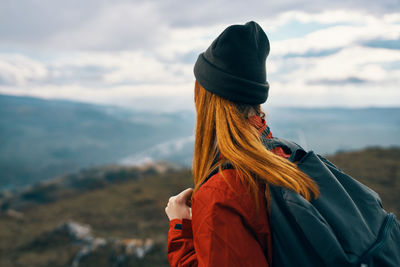 Rear view of woman walking on mountain against sky