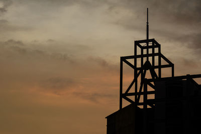 Low angle view of silhouette water tower against sky at sunset