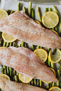 Raw pacific rockfish on a bed of asparagus and lemon wheels, sheet pan dinner, trout amandine 