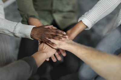 Closeup shot of group of unrecognizable people joining their hands together in huddle