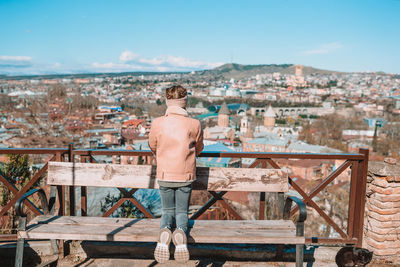 Rear view of shirtless man standing against buildings in city
