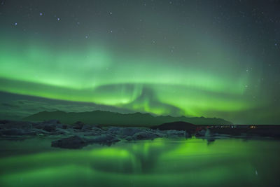 Scenic view of aurora borealis over lake against sky at night