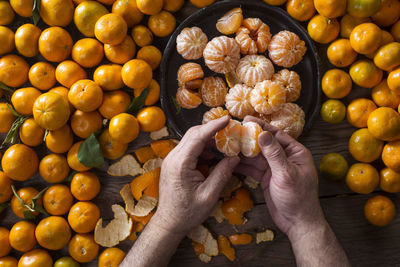 Cropped hands of man peeling orange fruits