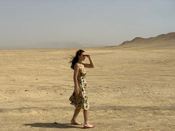 Woman wearing sunglasses while standing at desert