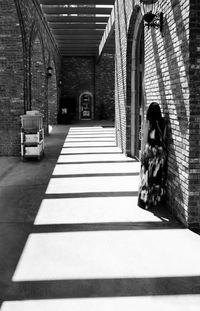 Rear view of fashion model standing by brick wall at hallway