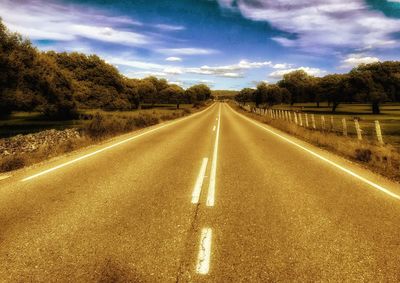 Empty road along landscape and trees against sky