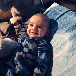 Portrait of smiling baby boy lying on bed