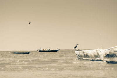 Boats sailing in sea against clear sky