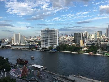 River by buildings in city against sky