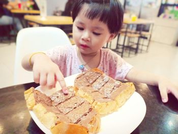 Girl holding ice cream in plate on table