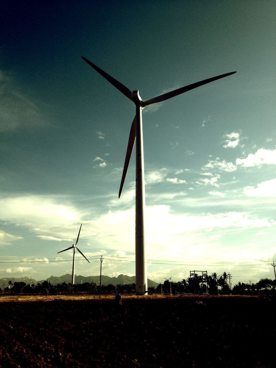 WIND TURBINE ON FIELD AGAINST SKY