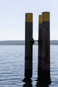 Wooden post in sea against clear sky