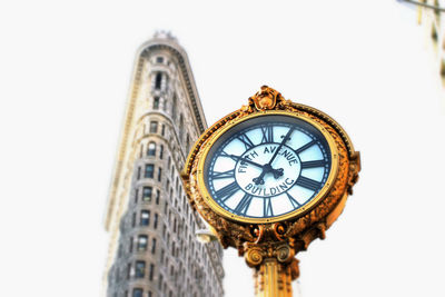 Low angle view of clock and flatiron building against sky