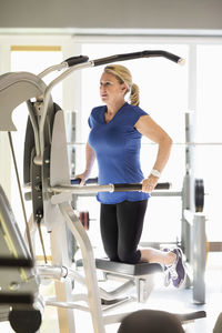Senior woman exercising on pull-up assist machine at gym