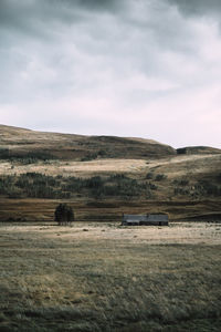 Scenic view of field with cottage in scottish highlands against sky